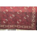 A large Bokhara carpet with typical geometric decoration upon a deep red ground, 380 x 280 cm