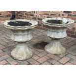 A pair of reclaimed garden urns of squat, circular and pleated form, with simulated ribbon bands