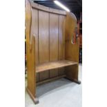 A reclaimed stripped pine settle with curved tongue and grooved boarded and winged back over a