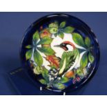 A boxed Moorcroft pottery plate with relief moulded woodpecker and horse chestnut detail 26 cm