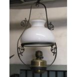 A Victorian hanging ceiling light with ironwork frame supporting a milk glass shade and brass font