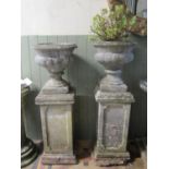 A pair of reclaimed garden urns of circular tapered and lobbed form with stepped sockles raised on