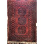 Full pile Afghan rug in the Bokhara manner with typical medallion decoration upon a deep red/burnt