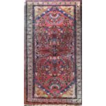 Small Persian rug decorated with floral sprays upon a coarse red ground, 120 x 70 cm