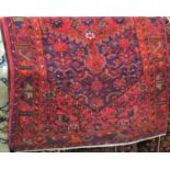 Full pile Persian Hamadan village rug with central red medallion framed by navy blue and red flowers