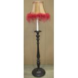 An ebonised wooden standard lamp in the form of a candle stand with turned stem, petal collar and