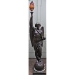 A large spelter torchere in the form of a winged angel, classically draped, standing upon a