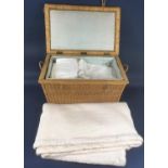 Vintage wicker basket with hinged lid containing white bed and table linen and lace together with