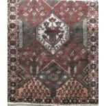 Persian full pile village rug decorated with panels of floral and paisley sprays, upon a dark red