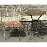 A small vintage and weathered green painted ironwork garden table with circular tin top, raised on