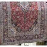 Good quality large Kashan carpet with typical scroll foliate decoration upon a red and navy