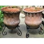 A pair of weathered terracotta planters, with crimped rims and circular bodies, raised on associated