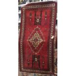 Belouch rug with central floral medallion and further still life's upon a red ground, 205 x 115 cm