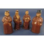 A set of four brown glazed decanters and stoppers in the form of oriental characters, a monk and a