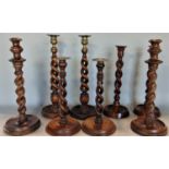 Two pairs of open barley twist wooden candlesticks, together with two further pairs of barley twists