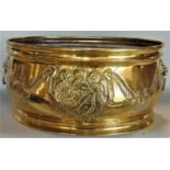 Large polished brass oval baluster jardinière embossed with a crest and floral garlands, with twin