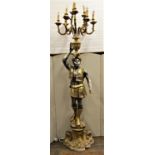 An Italian carved timber candelabrum with gold and silver lustred finish, the turbaned character