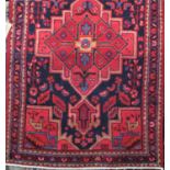 Persian full pile rug with central red floral medallion with navy borders upon a red ground, 170 x