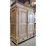 A 19th century European stripped pine wardrobe enclosed by a pair of fielded panelled doors