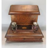 An Edwardian oak stationery box, the rising lid revealing a fitted interior, the base fitted with