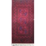 Small Bokara rug with three blue and red medallions upon a brick red ground, 180 x 90 cm