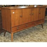A mid 20th century walnut veneered sideboard enclosed by four doors and two drawers with fixed