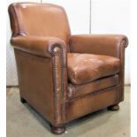 A tan leather upholstered easy chair with rolled arms and loose seat cushion, studded detail and