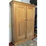 A stripped pine housekeepers cupboard, floorstanding and enclosed by a pair of full length moulded