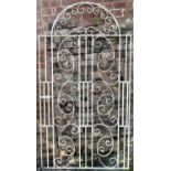 A reclaimed cream painted ironwork pedestrian side gate of stepped or shouldered arched form, with