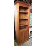 A modern stripped pine floorstanding side cupboard and combined shelving unit with three open