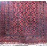 A good quality Persian rug with scrolled foliate decoration and good broad trim upon a red ground,