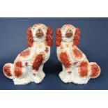 A pair of 19th century Staffordshire spaniels with red painted patches, 32cm tall approx