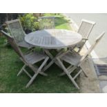 A good quality weathered teak folding garden table with circular segmented slatted top raised on x