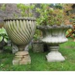 A reclaimed garden urn with circular tapered notched and wrythen fluted bowl, raised on a square cut