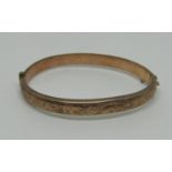 9ct hinged bangle with engraved scrolled decoration, 10.2g (dented)