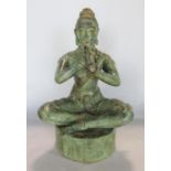 A bronze figure of an Eastern deity sitting cross legged and playing upon a flute