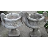 A pair of reclaimed trophy shaped garden urns, with scrolling relief detail and foliate socles