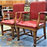 A pair of light oak framed open armchairs with faux leather upholstered seats, backs and arm pads