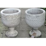 A pair of reclaimed planters of circular form with repeating relief detail, with foliate socles,