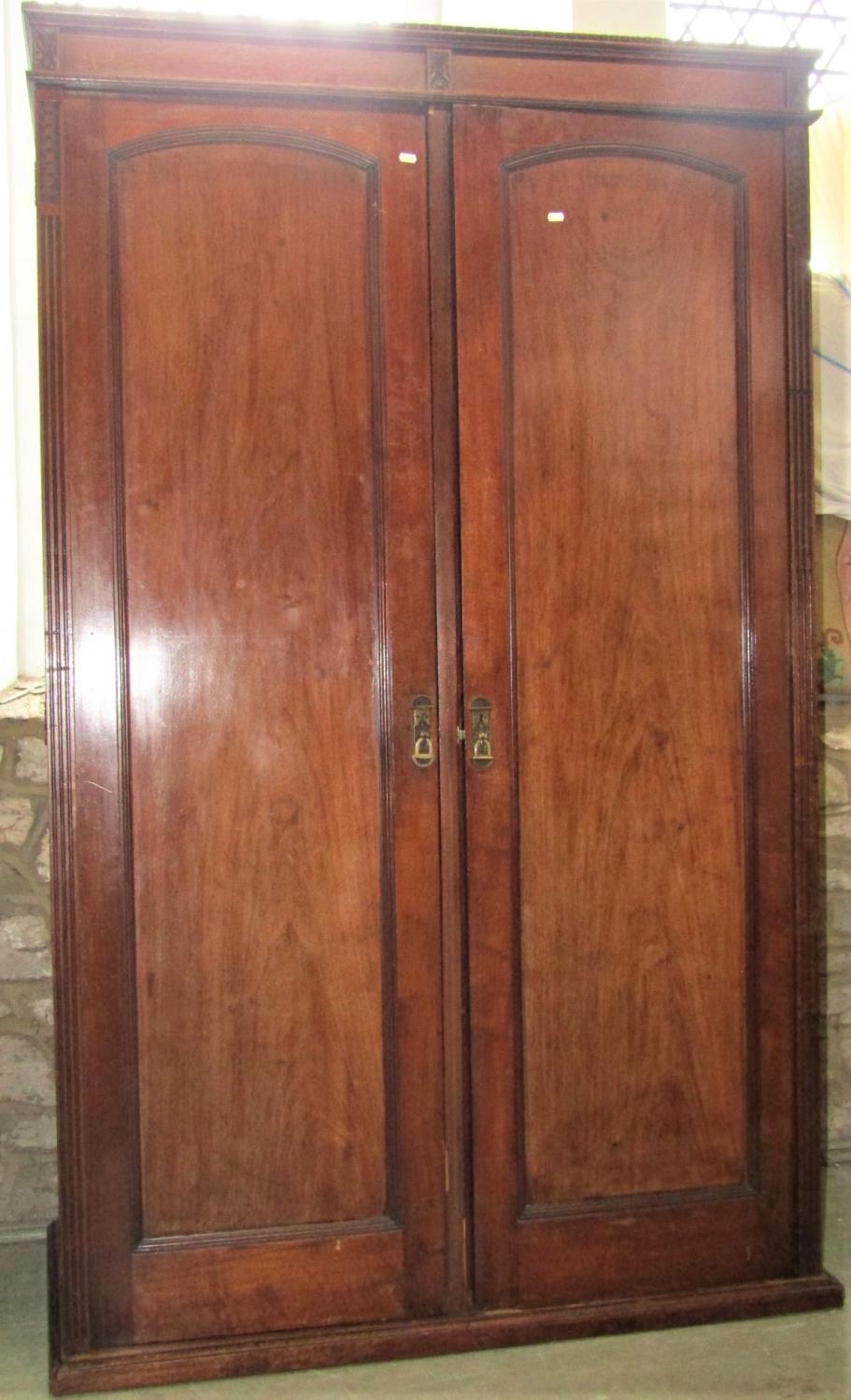 A late Victorian mahogany wardrobe enclosed by a pair of full length rectangular and arched