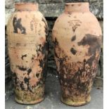 Two similar terracotta bottle shaped jars with ring necks, 80cm high approx