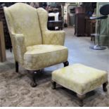 A Queen Anne style wing armchair with shaped outline and floral patterned upholstered finish on a