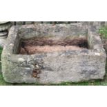 A weathered natural stone trough of rectangular form, thick walled, with cut out corner channel,