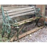 A two seat garden bench with green painted cast iron ends with lions mask and scrolled detail,