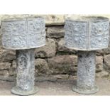 A pair of lead planters of circular form with scrolling foliate relief, raised on cylindrical