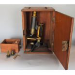 A brass microscope by R & J Beck Limited of London number 26035 with a total of four lenses in a