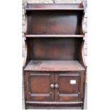 An Ercol waterfall bookcase in a mid brown colour, the lower section enclosed by a pair of