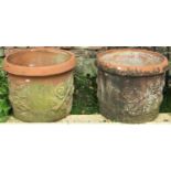 A pair of weathered terracotta planters of squat cylindrical form with moulded rims and repeating