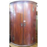 A Georgian mahogany bow fronted hanging corner cupboard with chequered string inlaid detail and