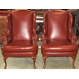 A pair of Queen Anne style wing armchairs with brown faux leather upholstered finish and loose axe